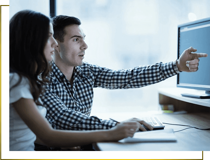 A man and woman sitting at a desk with a computer.